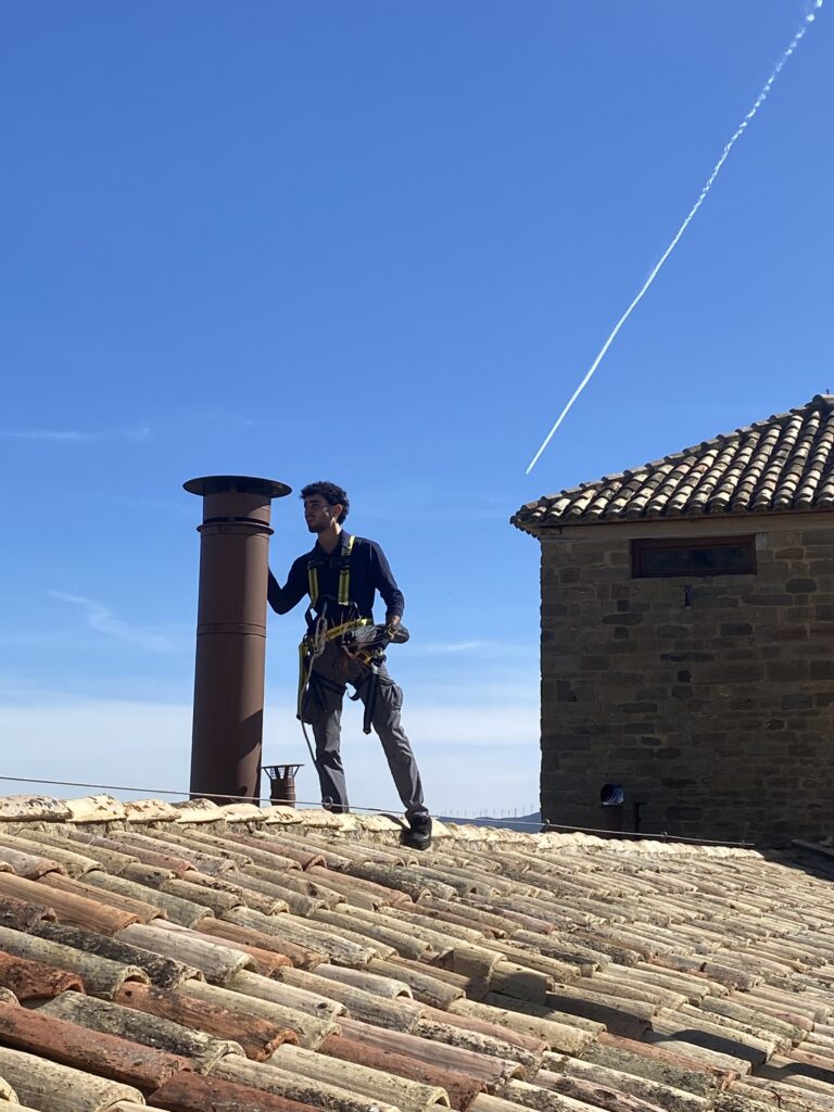 Deshollinador profesional de Lasua trabajando junto a una chimenea en el tejado